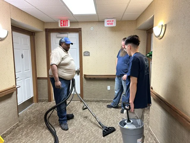 Bayou City crew extracting water in a commercial hallway using industrial vacuum equipment during an emergency call